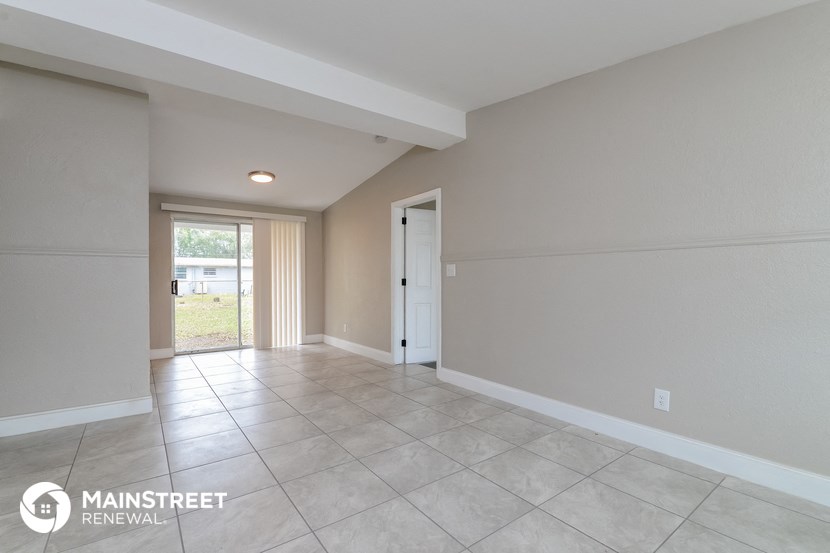 the spacious living room with tile flooring and white walls