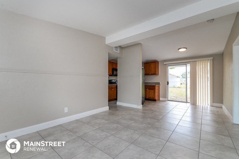 an empty living room with a door to the kitchen