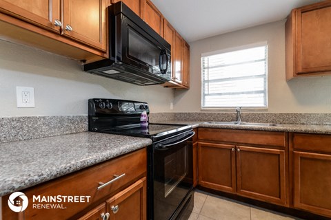 a kitchen with black appliances and granite counter tops and wooden cabinets