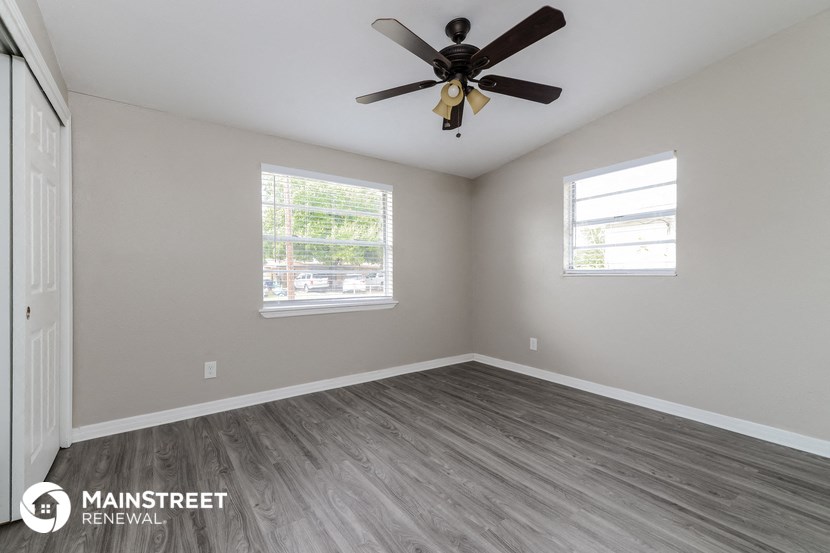 the spacious living room with wood floors and a ceiling fan