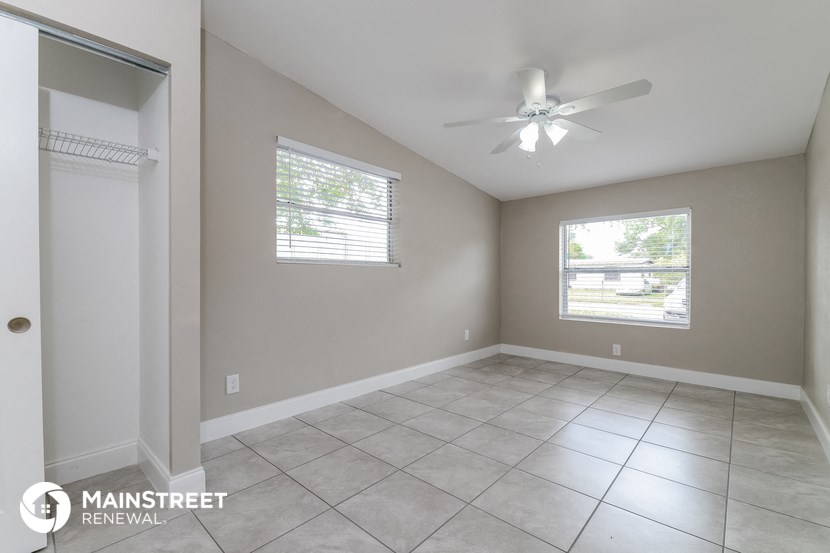 an empty living room with a ceiling fan and a window