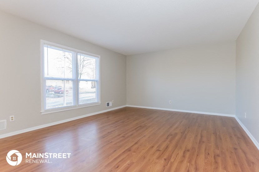 the living room of a home with wood floors and a large window