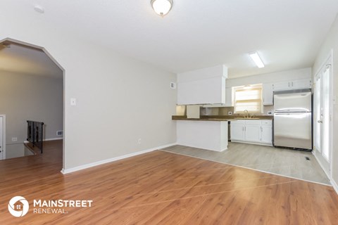 the living room and kitchen with wood flooring and white cabinets