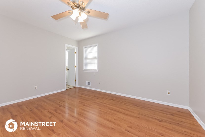 the spacious living room with wood flooring and a ceiling fan