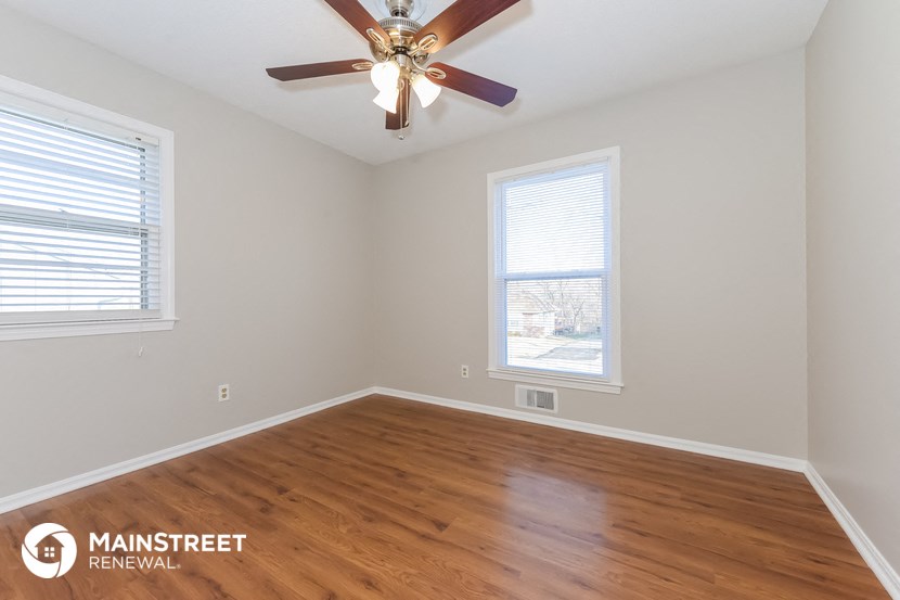 the living room with wood floors and a ceiling fan