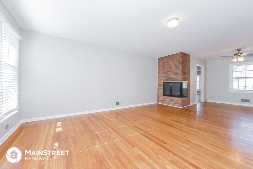 the living room with wood floors and a fireplace