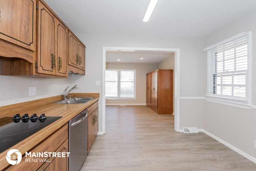 a kitchen and hallway with wooden cabinets and a sink