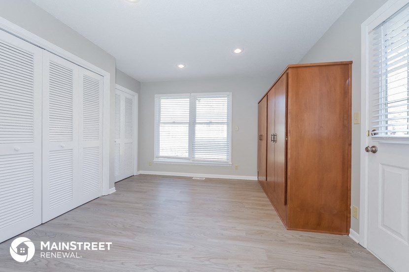 a master bedroom with wood floors and white closets