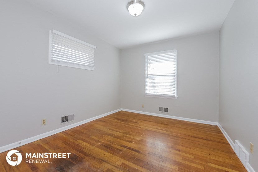 the spacious living room with wood flooring and white walls