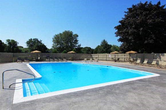 a swimming pool with a fence and chairs around it