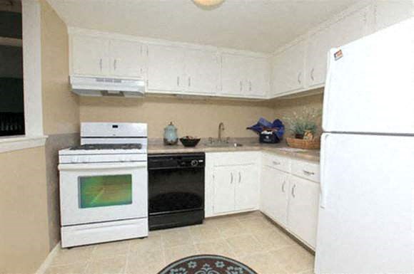 a white kitchen with a stove and a refrigerator