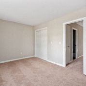 an empty bedroom with a door to a closet