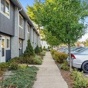 a long sidewalk with cars parked in front of houses