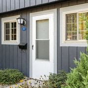 a white door on a blue house with two windows
