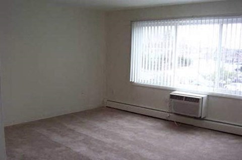 an empty living room with a window and a heater