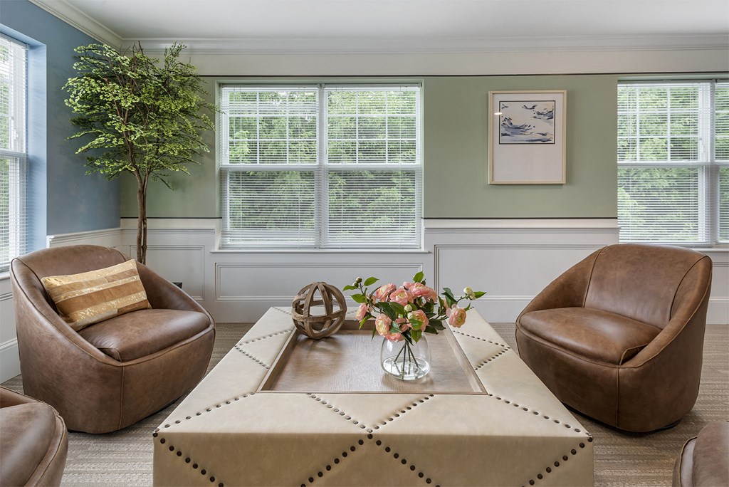 a living room with chairs and a table with a vase of flowers