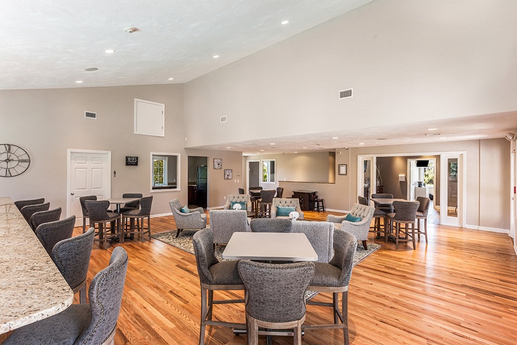 a large living room with tables and chairs and a kitchen