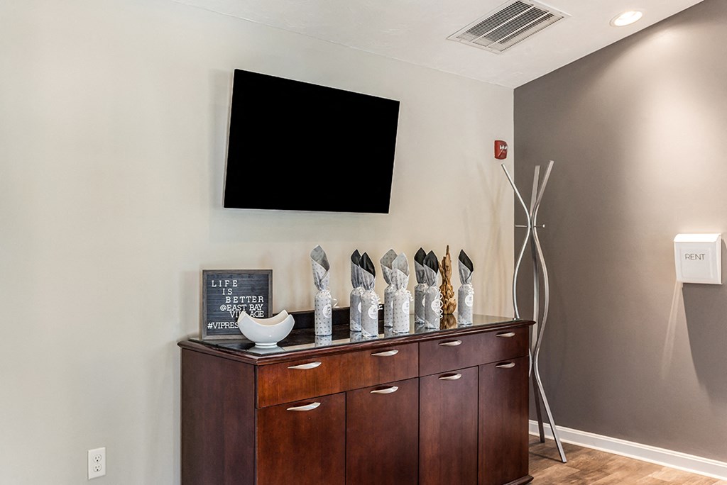 a room with a wooden dresser and a tv on the wall