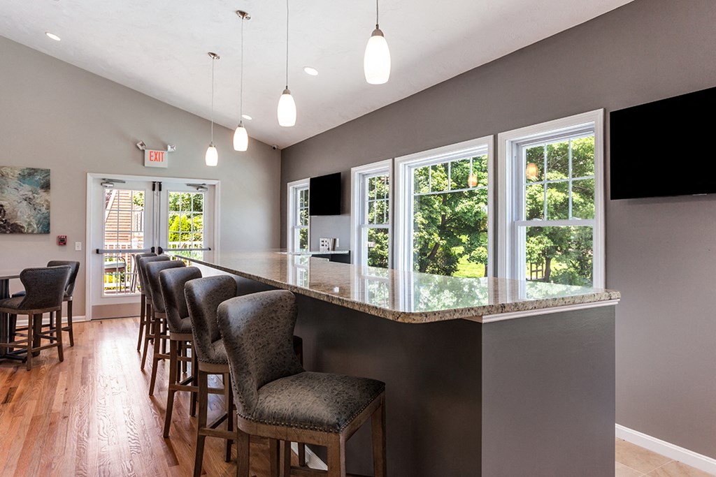 a bar with chairs in a room with windows