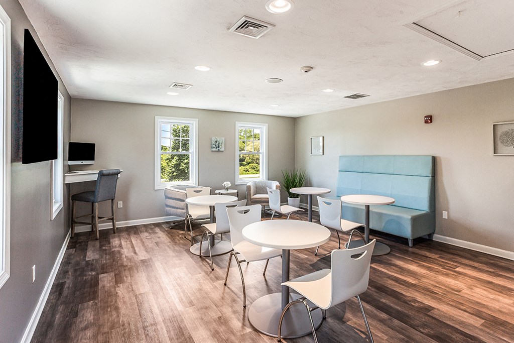 a community room with tables and chairs and a tv