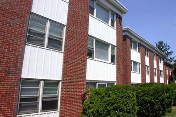an apartment building with a red brick facade and green bushes