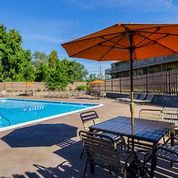 a swimming pool with a table and chairs under an umbrella