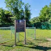 a park with a sign in front of a fence