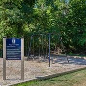 a park with a chain link fence and a blue sign