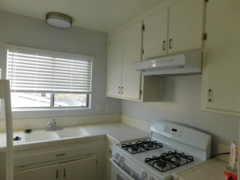 a kitchen with a stove and a sink and a window
