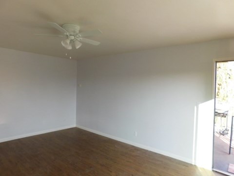 an empty living room with a ceiling fan