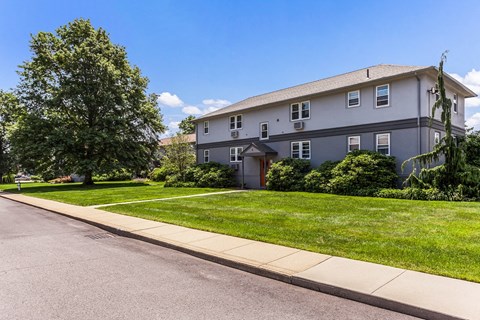a white house with a sidewalk and lawn in front of it