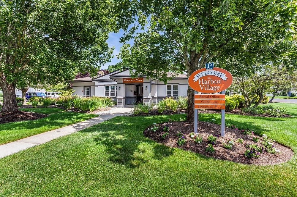 a sign in front of a house with trees and grass