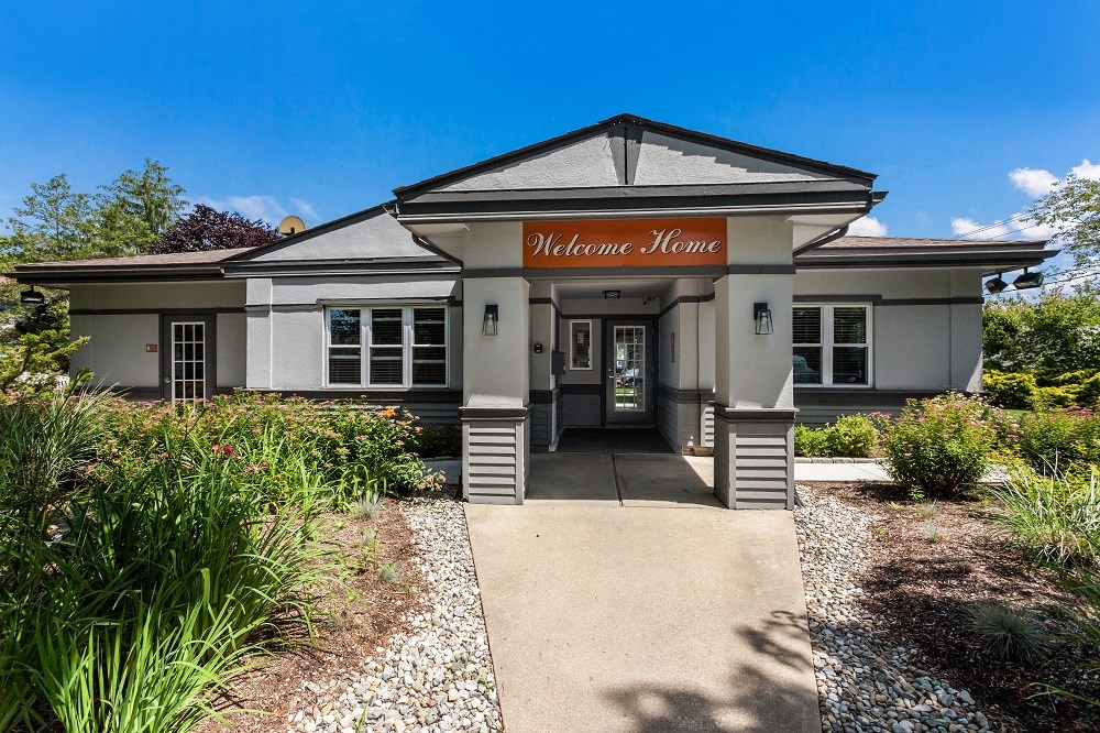 the welcome home entrance of a building with a sidewalk and plants