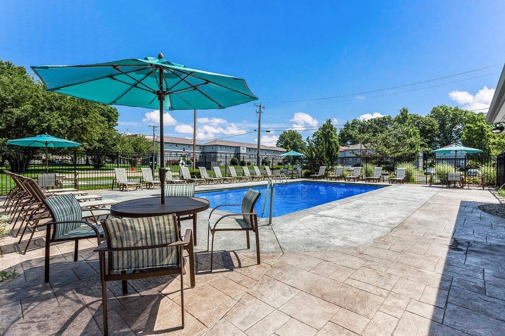 a swimming pool with patio furniture and umbrellas
