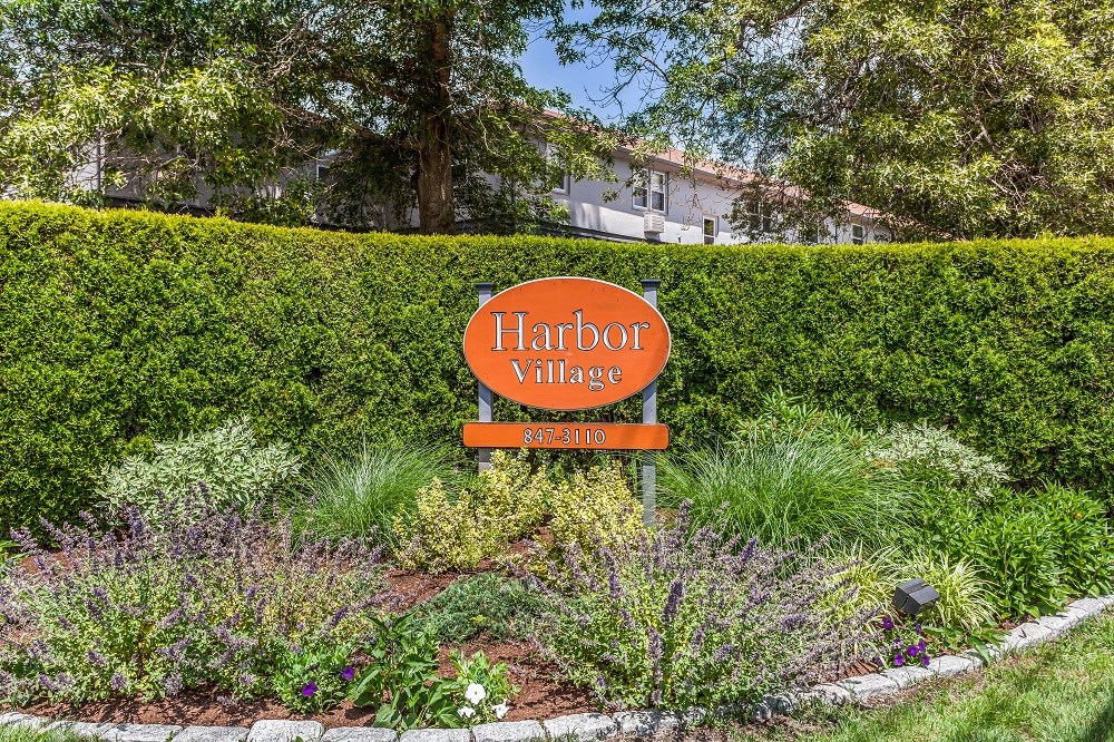 a sign in a garden in front of a hedge