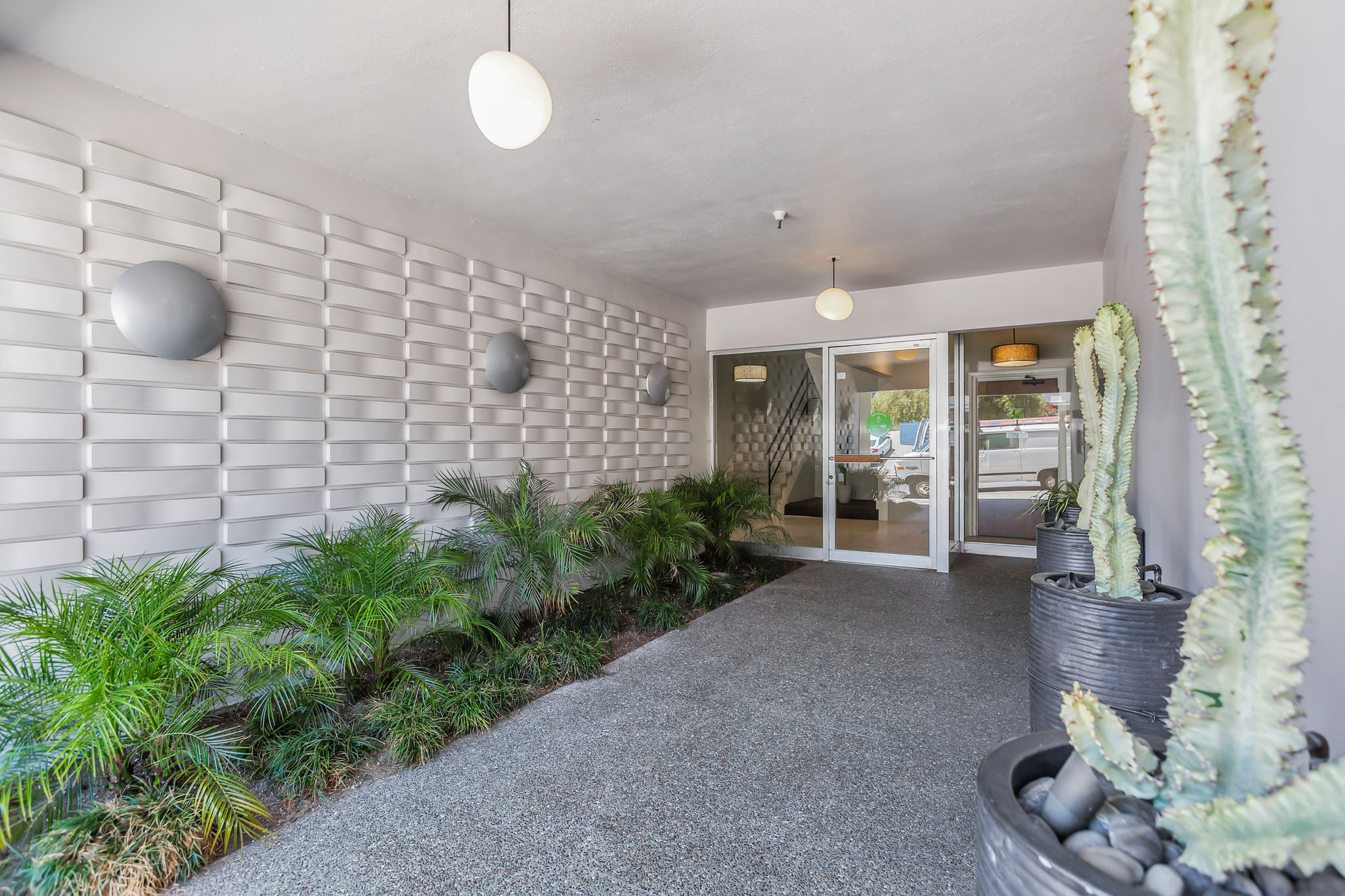 a courtyard with plants and a white brick wall