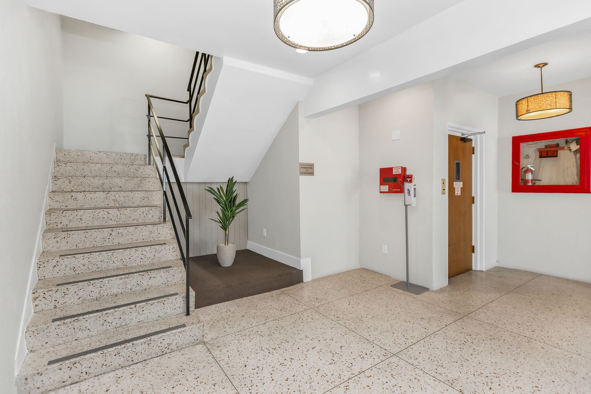 the landing lobby of a building with a staircase and a potted plant