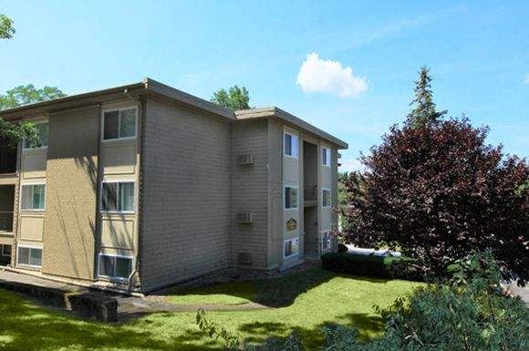 an apartment building with a red tree in the background