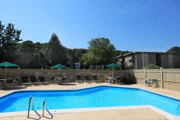 a blue swimming pool with chairs and umbrellas
