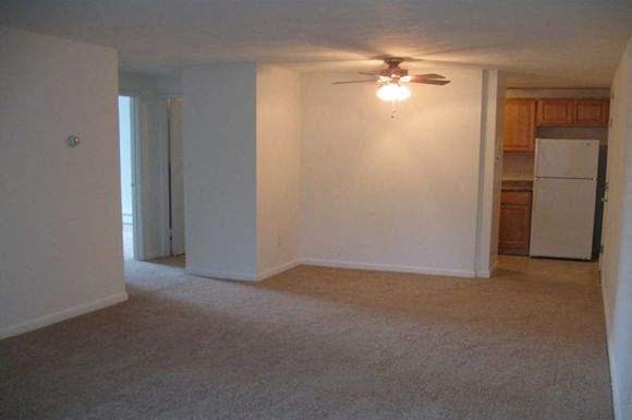 an empty living room with a ceiling fan
