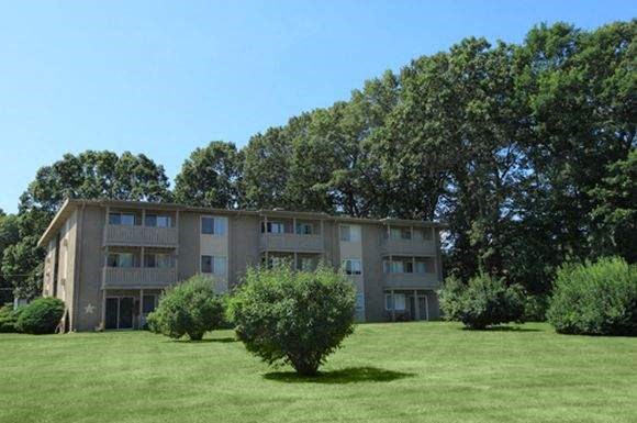 an apartment building on a green lawn with trees