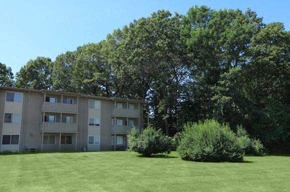 an apartment building with a green lawn and trees