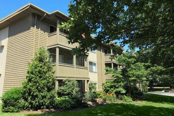 an apartment building with trees and bushes in front of it