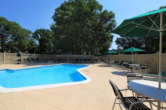 a swimming pool with chairs and tables and umbrellas
