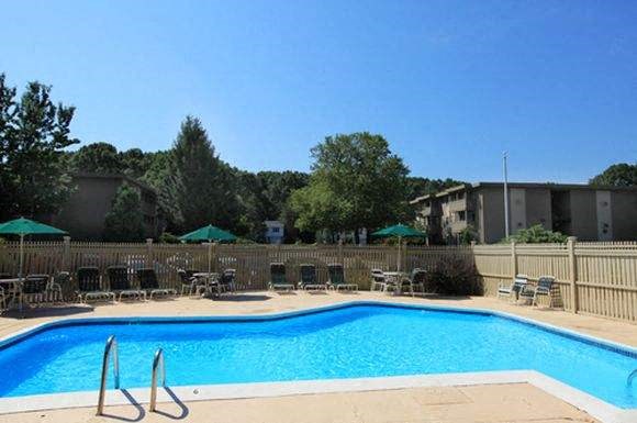 a blue swimming pool with chairs and umbrellas