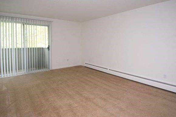 an empty living room with white walls and a large window