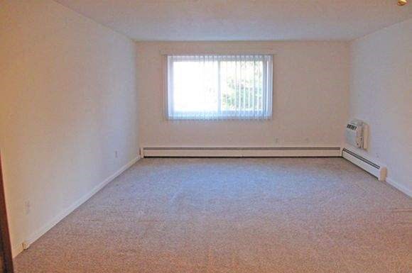 an empty room with a window and a carpet floor