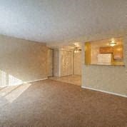 an empty living room with a ceiling fan and an open door
