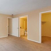 an empty living room with an open door to a bathroom