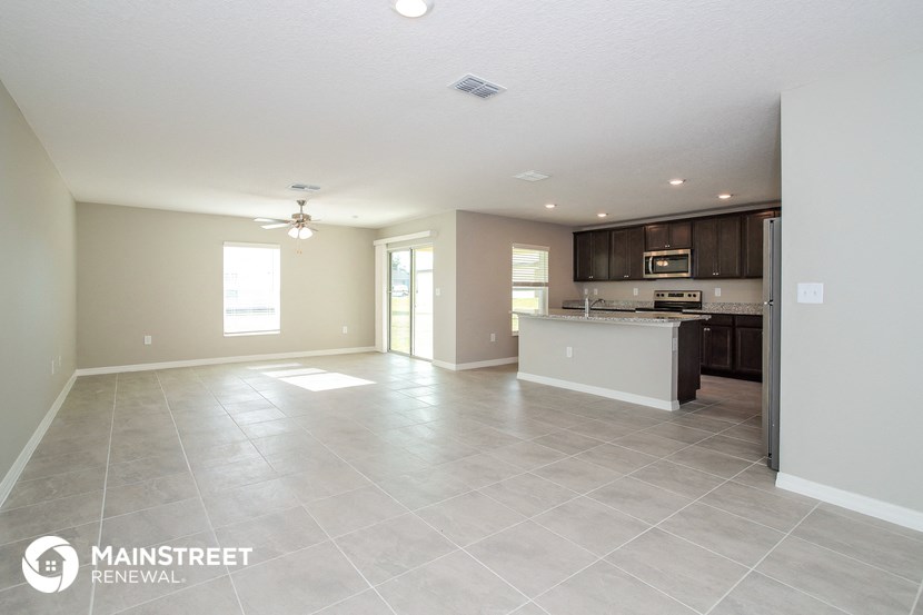an open kitchen and living room with tile flooring